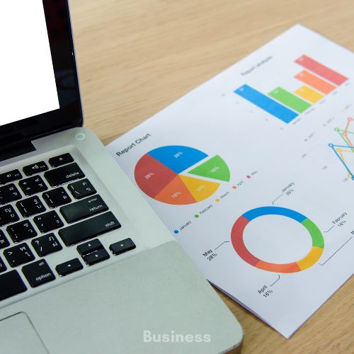 Table with a laptop and piece of paper on it illustrating graphs